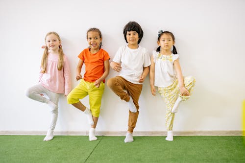 Kids Standing and Balancing On One Foot On A Green Carpet