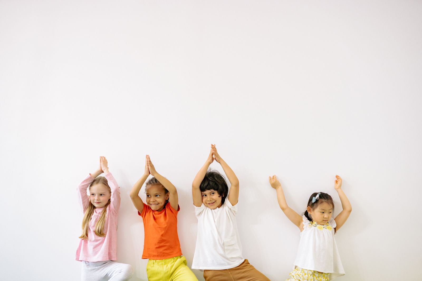 Four children practicing easy yoga poses together indoors on mats