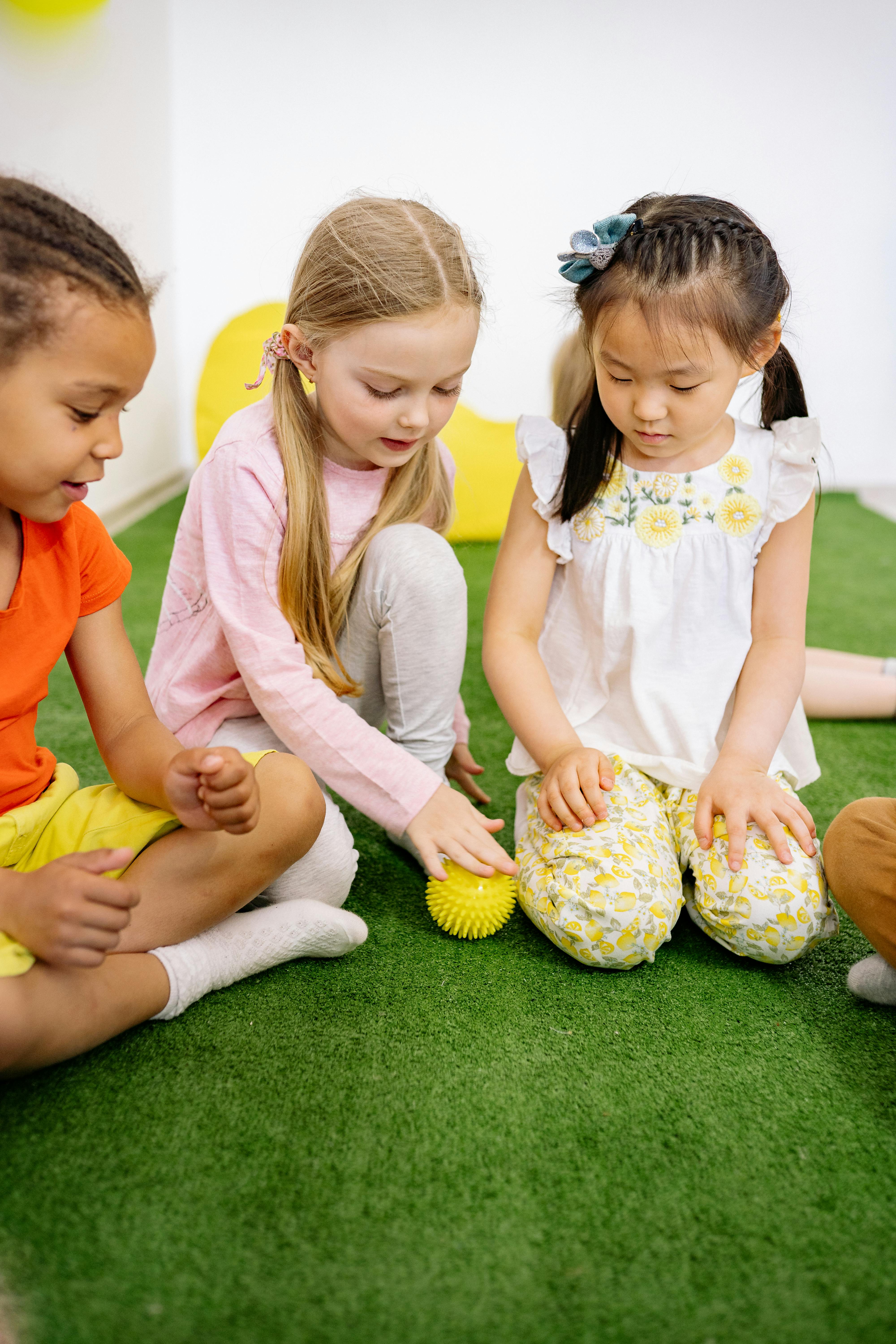 three girls playing with a yellow ball