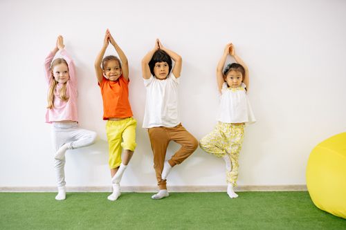 Free A diverse group of children enjoying a yoga session indoors, expressing joy and balance. Stock Photo