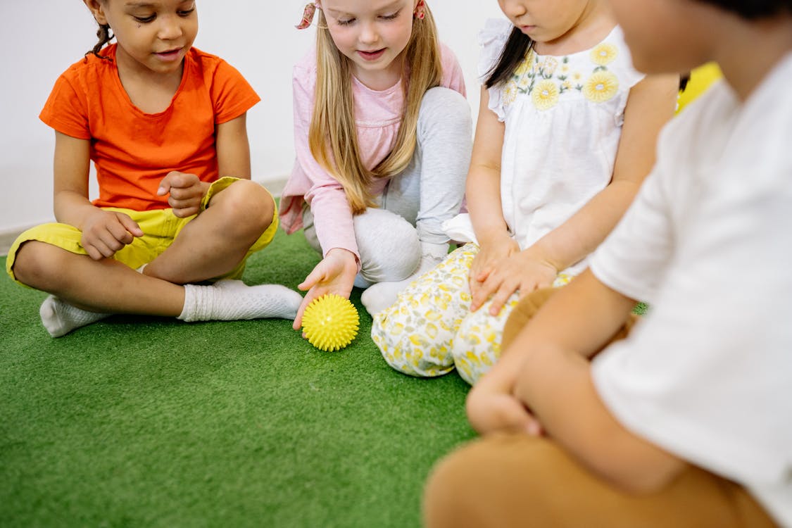 Children Playing With A Yellow Ball on Green Grass Carpet 