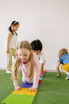 Happy children playing on colorful mats in an indoor playroom.