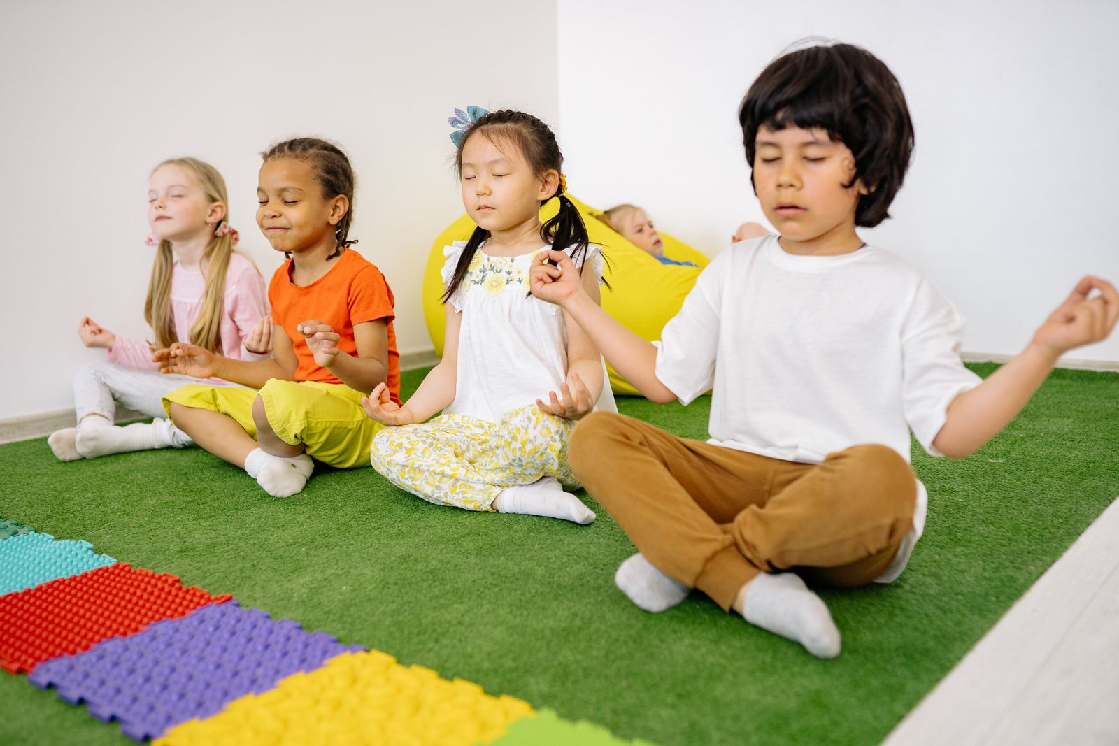 Group of students in a classroom practicing a seated yoga pose together on mats