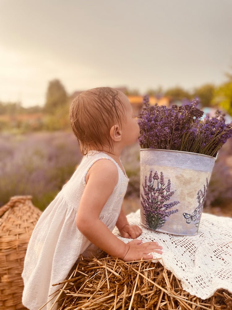 Girl Smelling Purple Flowers In A Bucket