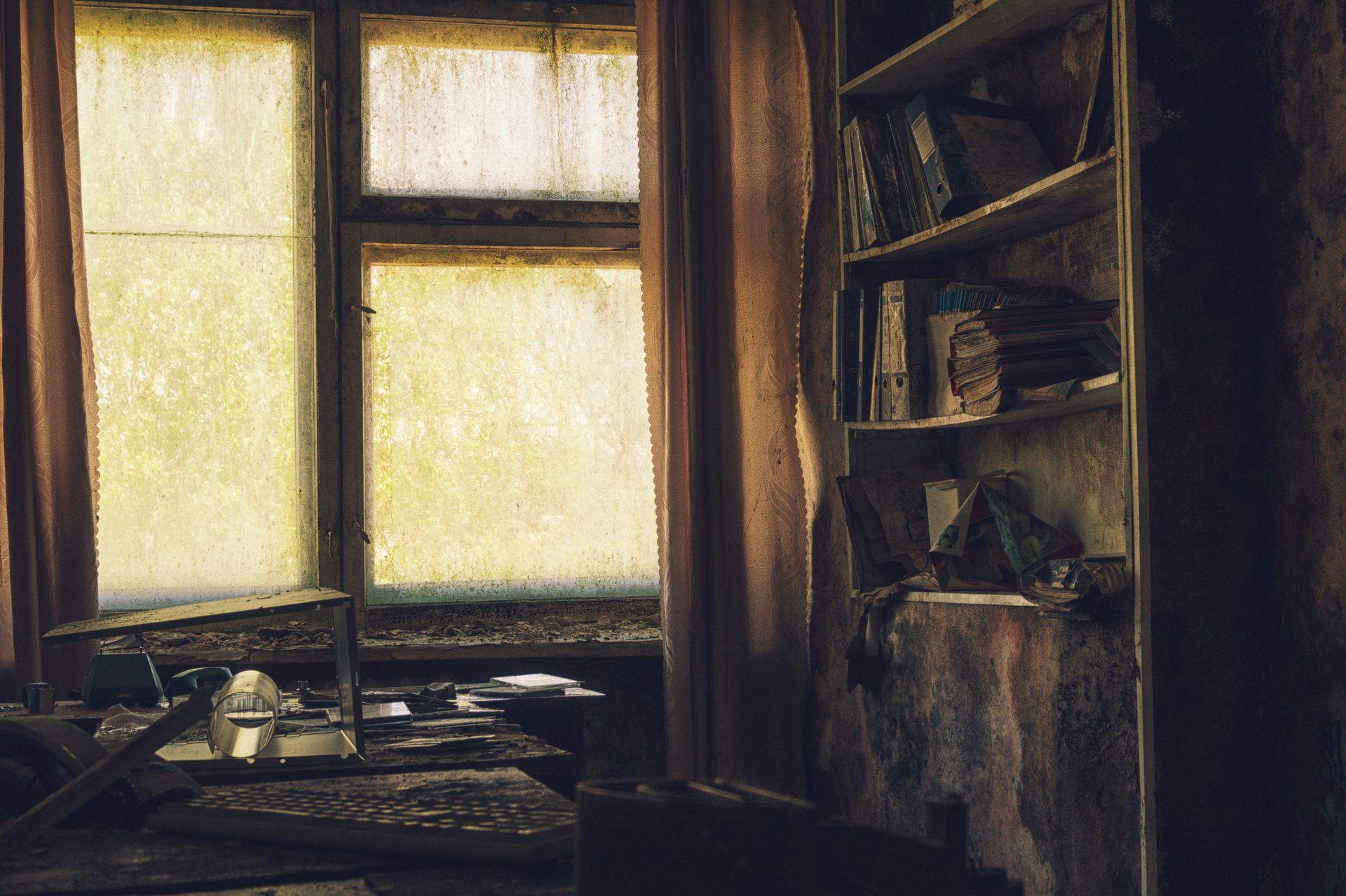 A dimly lit, abandoned office interior with dusty shelves and a yellow-lit window casting shadows.