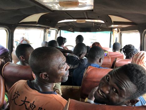 Interior view of a crowded bus with diverse passengers in Kumasi, Ghana.