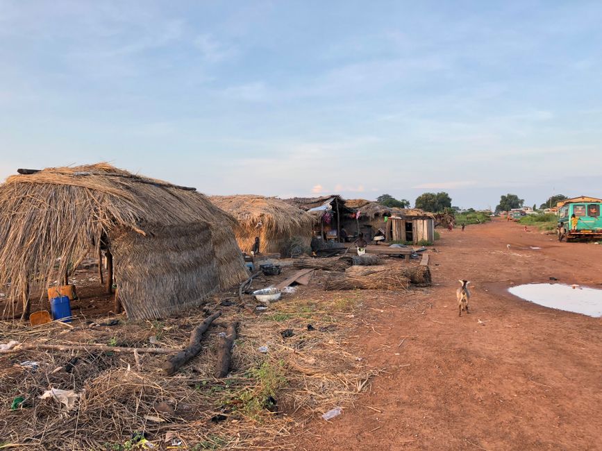 Rural scene of traditional huts in Kpando, Ghana, showcasing village lifestyle under a bright sky.