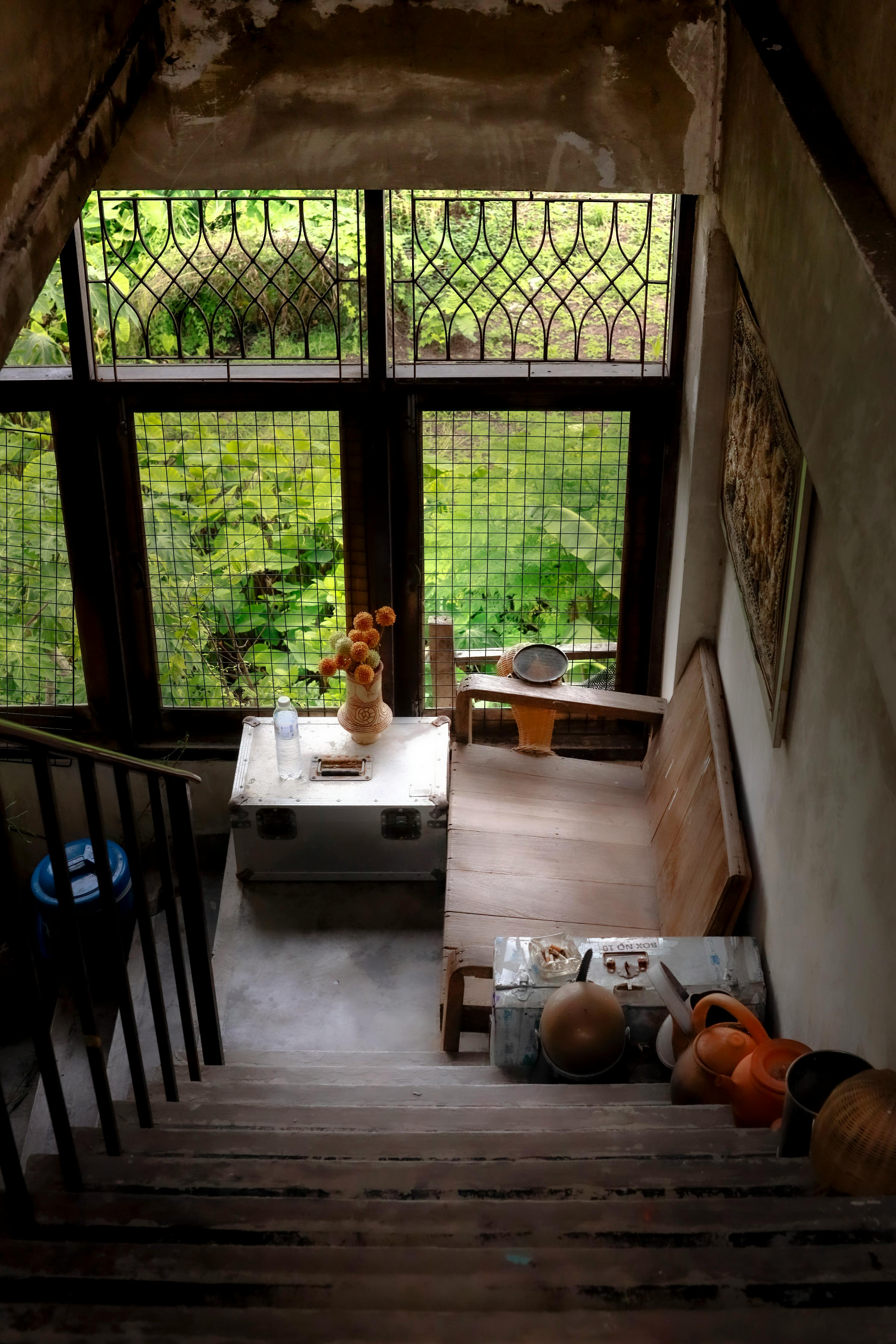 Free Rustic interior featuring a cozy wooden chair by a large window, overlooking vibrant greenery. Stock Photo
