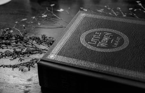 Grayscale Photo of a Book on a Wooden Surface