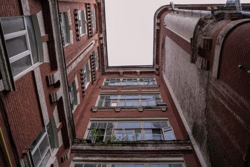 Free Low angle shot of a classic brick building facade with large windows and intricate design details. Stock Photo