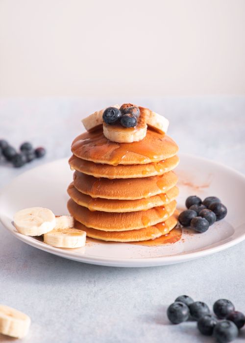 Free Mouthwatering pancakes topped with fresh bananas and blueberries, perfect for breakfast. Stock Photo