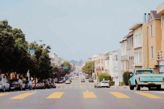A typical San Francisco street with parked cars and residential buildings.