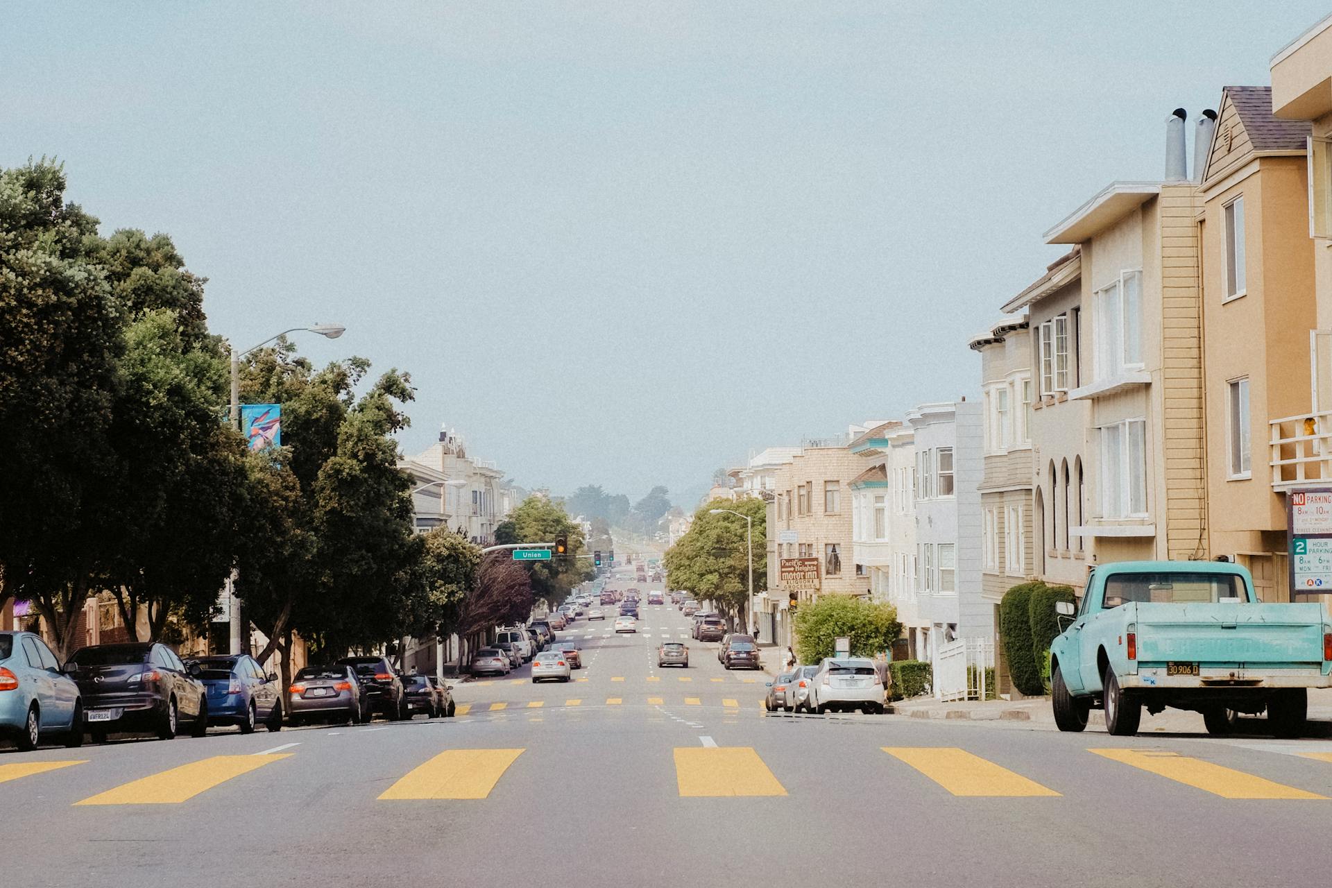 A typical San Francisco street with parked cars and residential buildings.