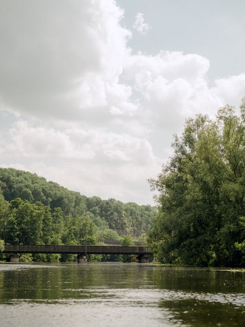 Free Tranquil river landscape with bridge and lush green trees under a cloudy sky in Wetzlar, Germany. Stock Photo