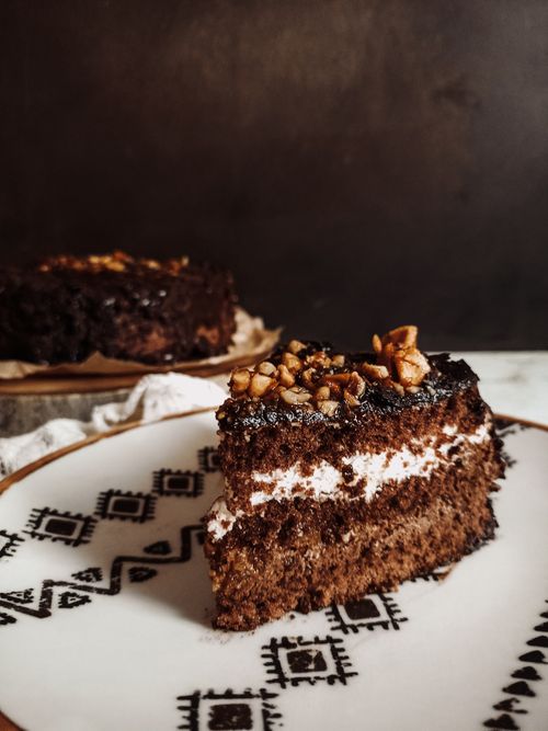 Free Rich chocolate cake slice with nuts on a decorative plate - perfect for dessert lovers. Stock Photo