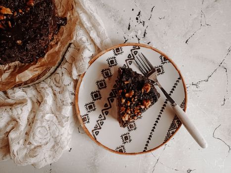 Delicious chocolate cake slice with nuts on a decorative plate, shot from above.