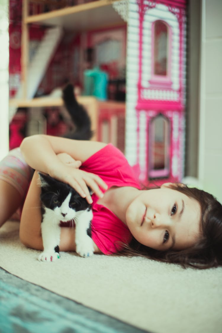 Kid Lying On The Floor While Holding A Cat