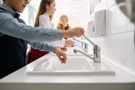 Woman in Blue Long Sleeve Shirt Washing Her Hand