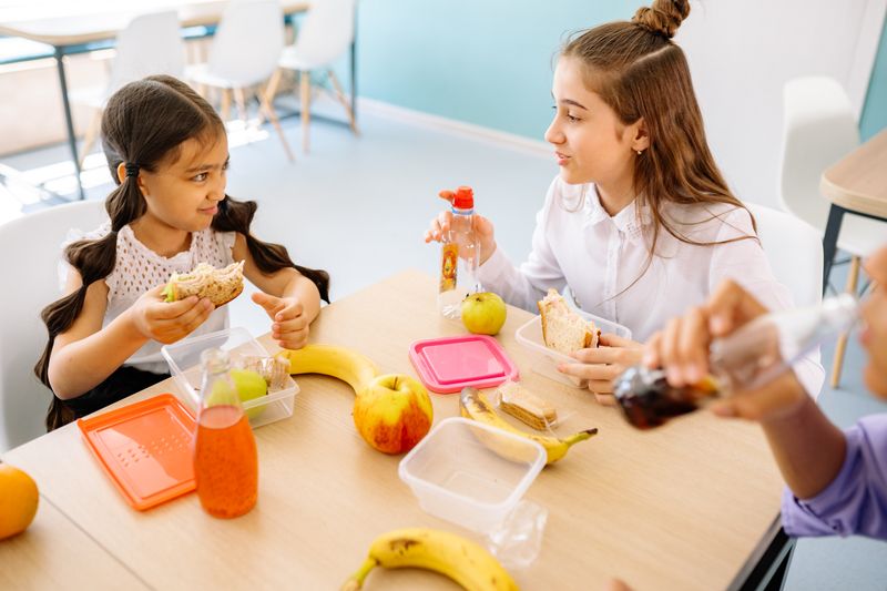 Anak-anak menikmati waktu makan siang dengan makanan dan minuman di sekolah