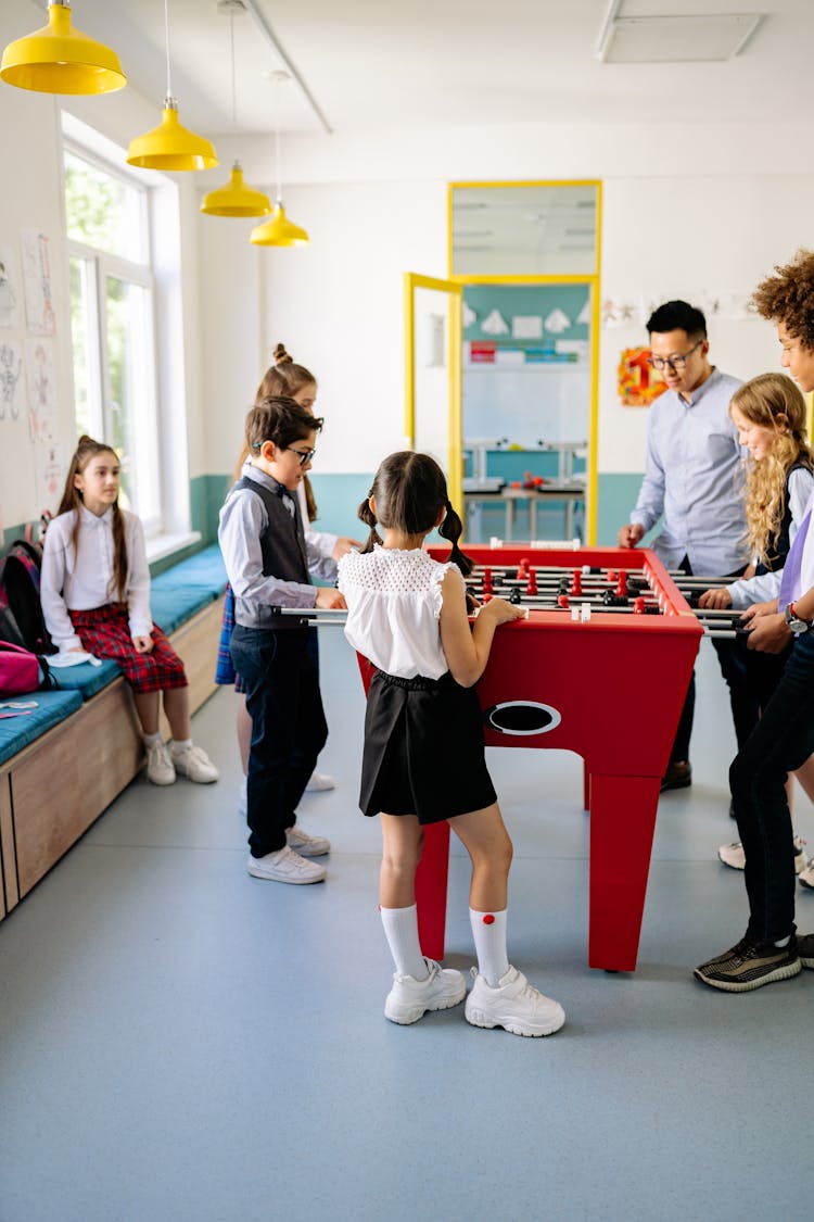 Kids Standing Beside Red Foosball Table