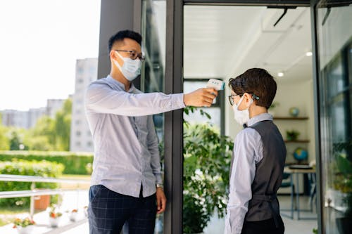 Free A Man Checking a Boy's Temperature by a Doorway Stock Photo