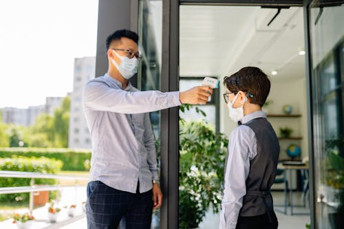 A Man Checking a Boy's Temperature by a Doorway