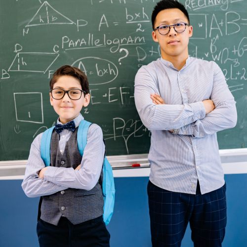 Free Teacher and student posing confidently in front of a blackboard with math equations. Stock Photo