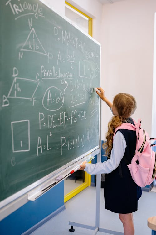 Free Girl Carrying Pink Backpack Writing on Blackboard Stock Photo