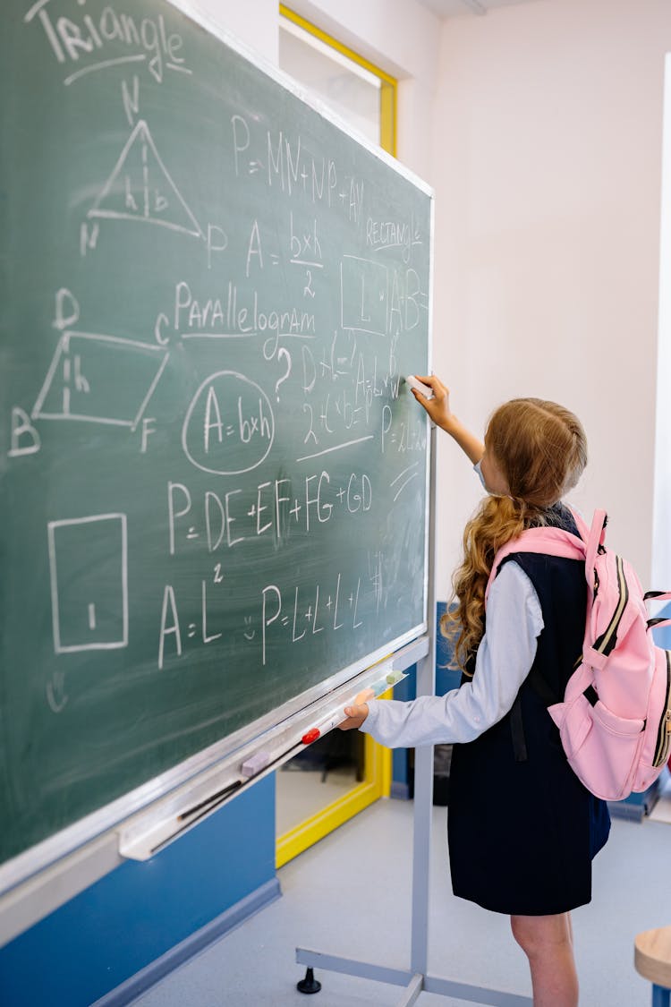 Girl Carrying Pink Backpack Writing On Blackboard