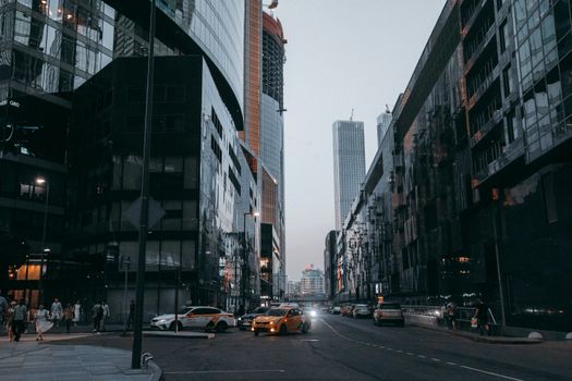 Dynamic cityscape at dusk with tall buildings and bustling street life in a modern metropolis.