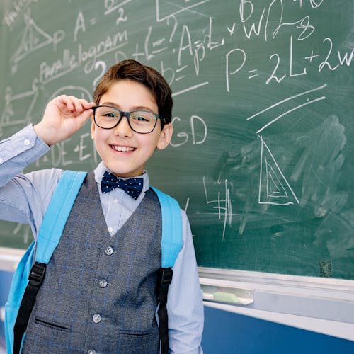 Free A Well Dressed Student Smiling in Front of a Chalkboard  Stock Photo