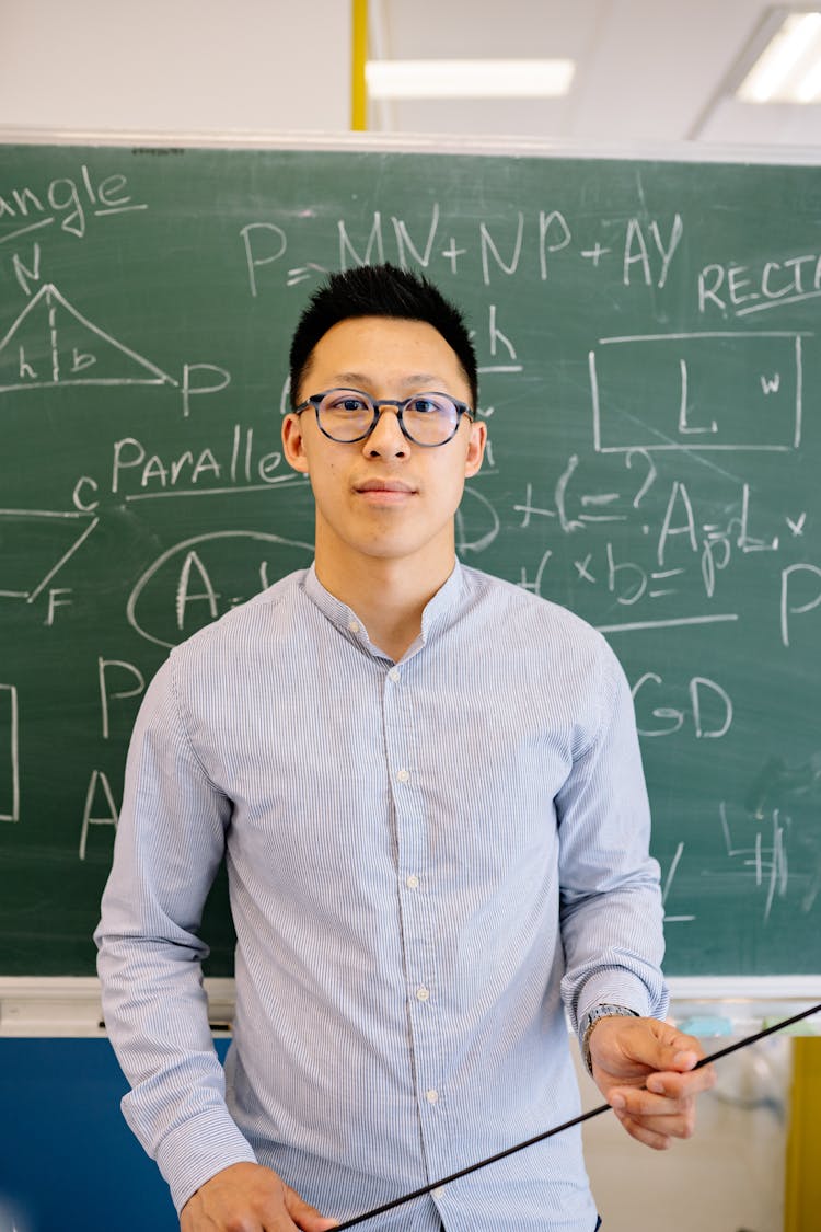 A Male Teacher In Blue Long Sleeve Shirt Looking At Camera