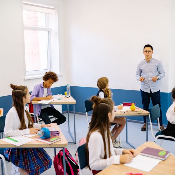 Professor orientando crianças em sala de aula: Licenciatura em Pedagogia EAD em 2 anos