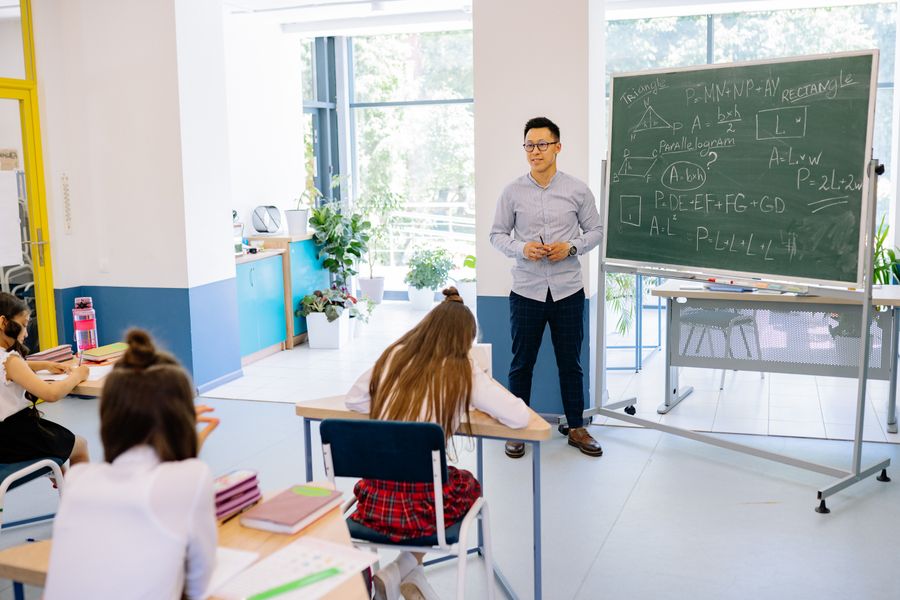 Teacher standing by a blackboard in a classroom