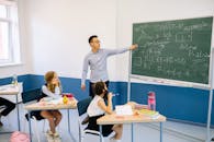 A Man Pointing at a Blackboard While Teaching a Class