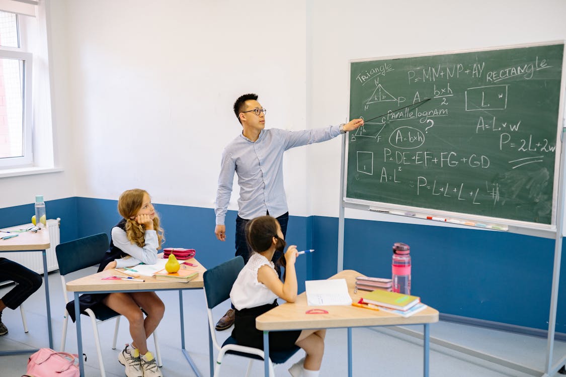 A Man Pointing at a Blackboard While Teaching a Class