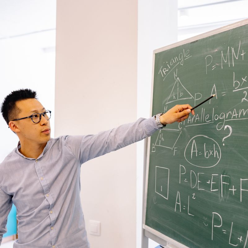 Profesor explicando en la pizarra a un grupo reducido