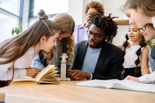 Students and teacher engage in science lesson using a microscope, fostering curiosity and learning.