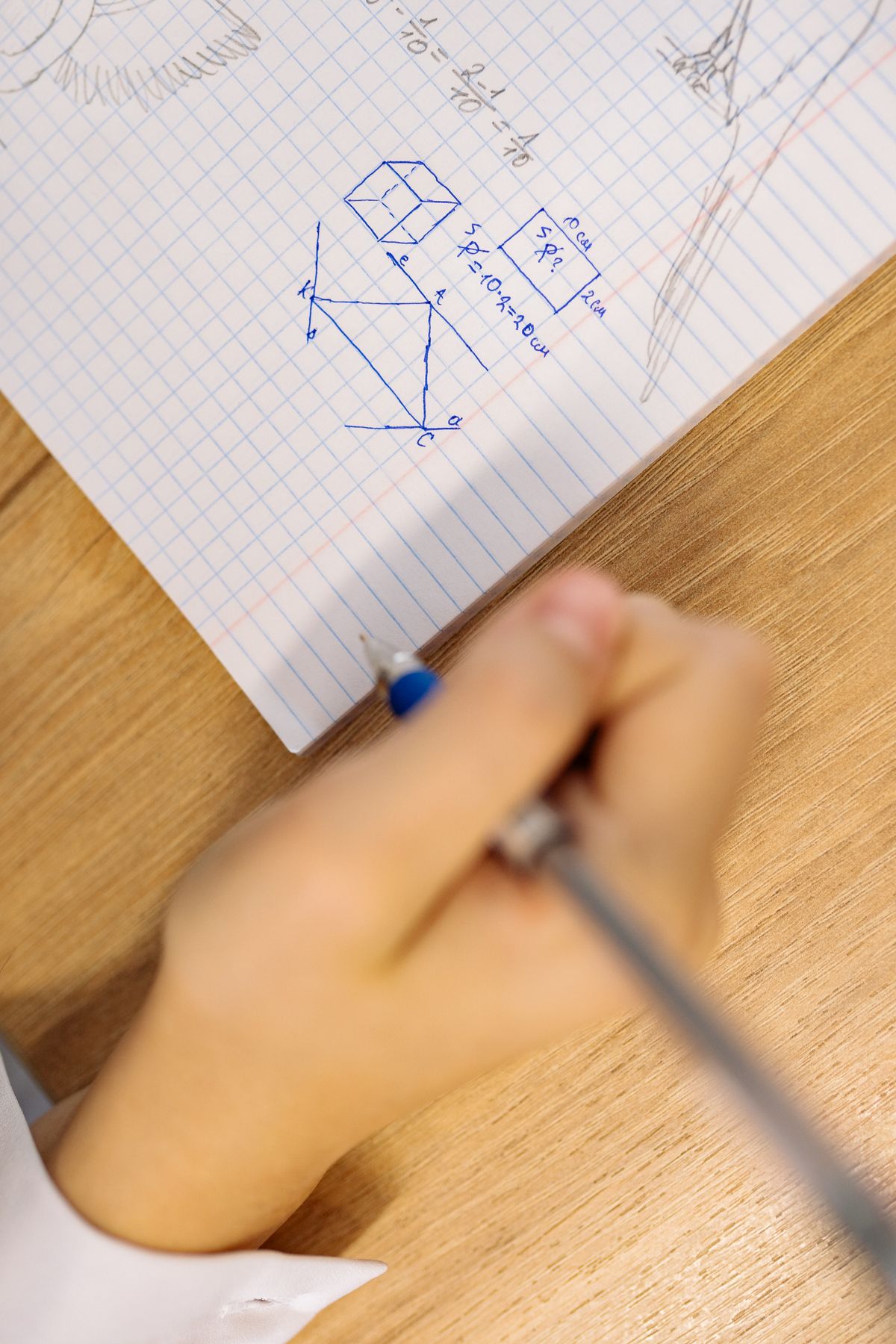 Hand writing mathematical equations and geometrical diagrams in a revision notebook
