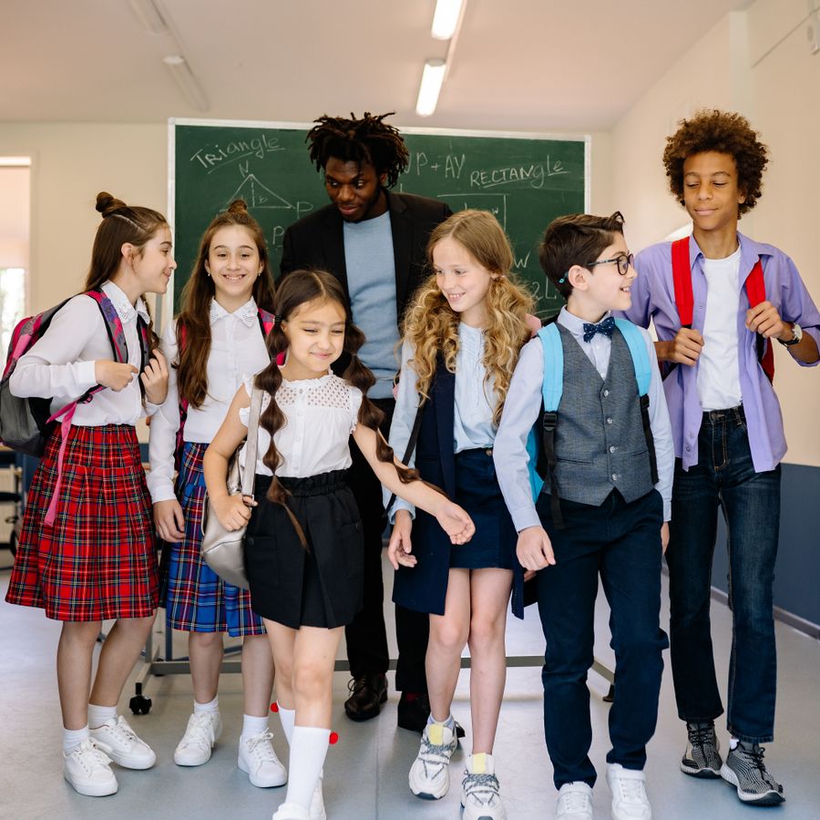 Children walking through a school with their teacher