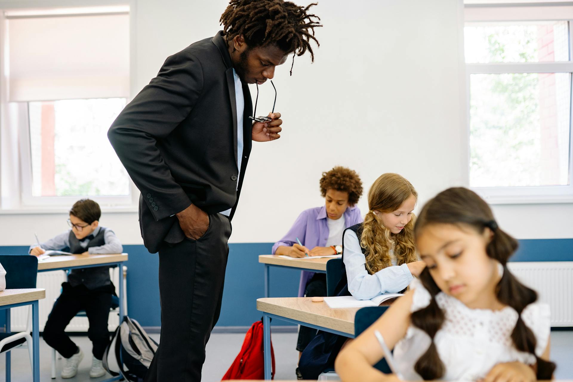 Teacher guides diverse students during class work in an interactive classroom setting.