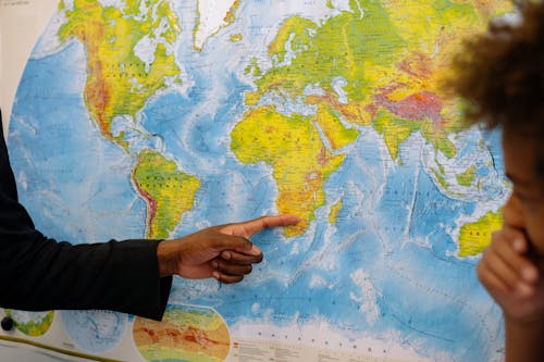 A Person in a Blazer Pointing at a Map of the World