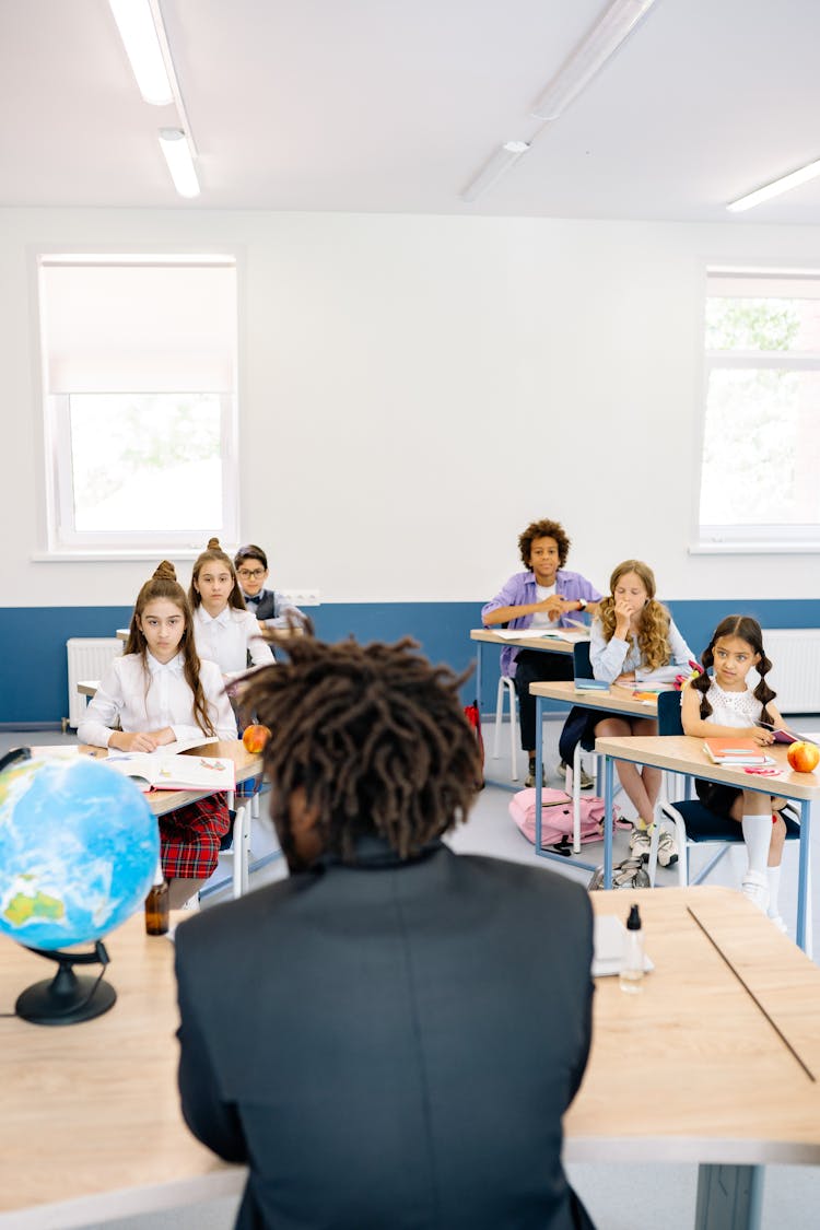 Young Students Listening To Their Teacher In A Class