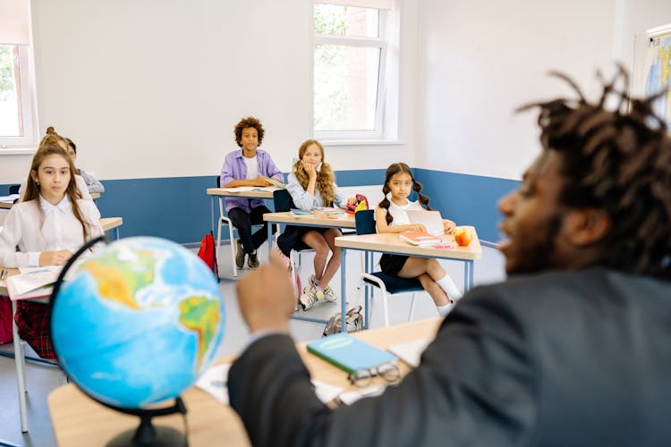 Young Students Listening To Their Teacher In A Class