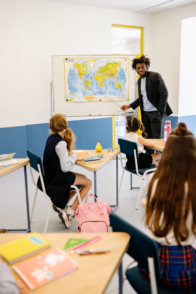 Man Teaching The Students About The World Map