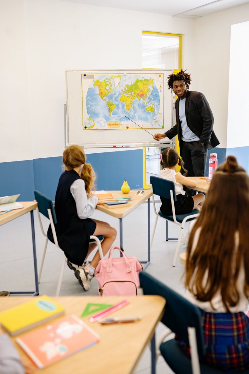 Teacher engaging students with a world map during a classroom geography lesson.