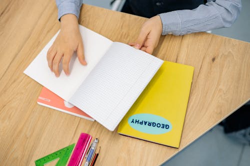 Free A Kid Holding a Notebook on a Wooden Desk Stock Photo