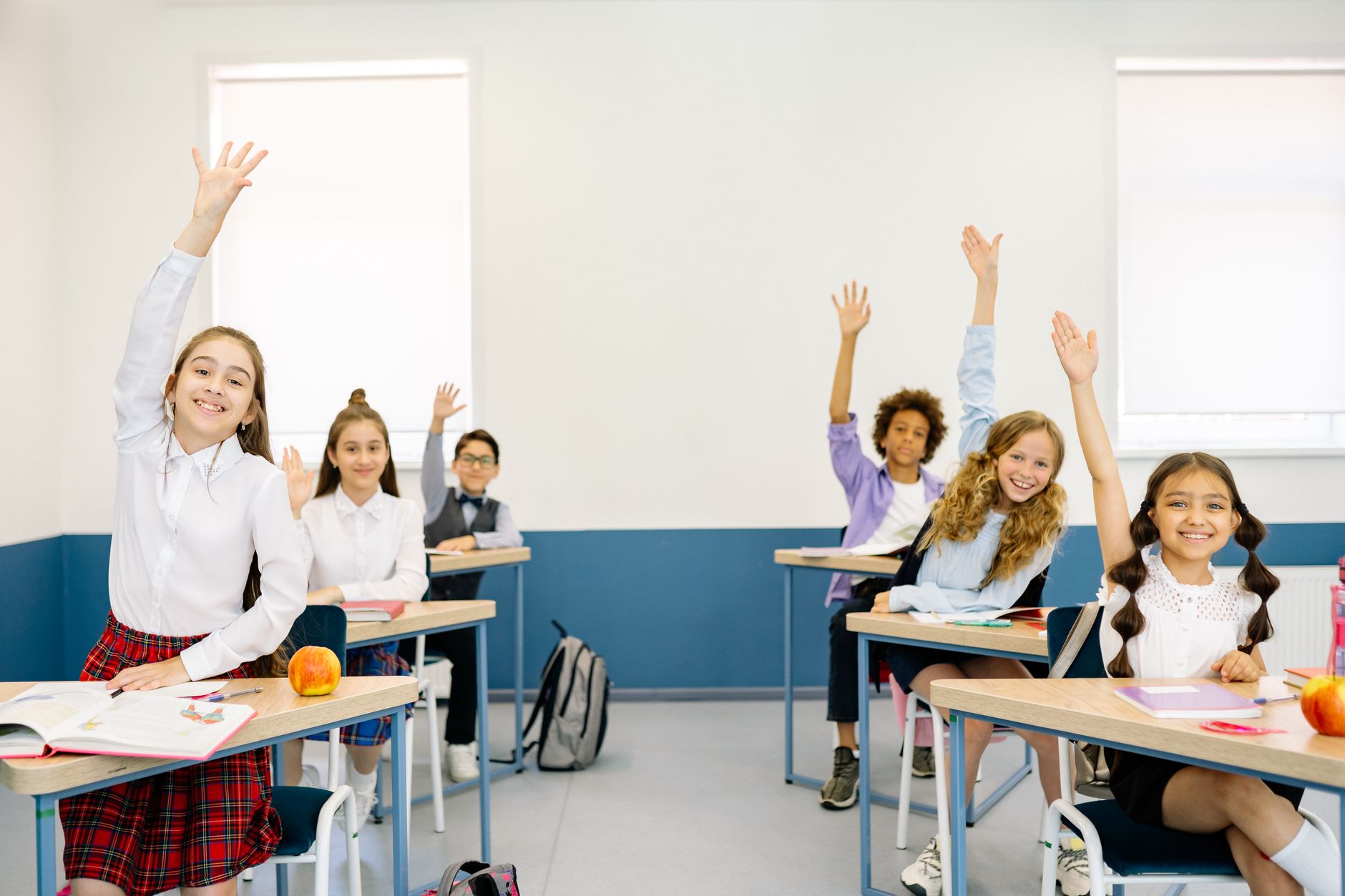 從資訊蒐集到價值創造:數位時代學習與表達力指南 Group of diverse children eagerly raising hands in a bright classroom setting.