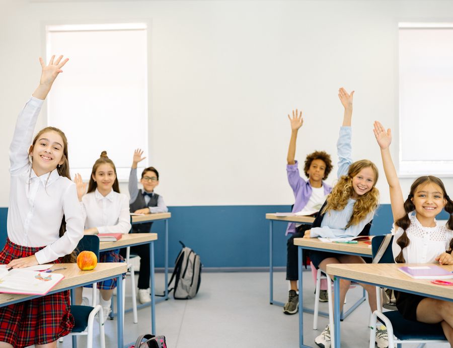 Happy students raising their hands in class