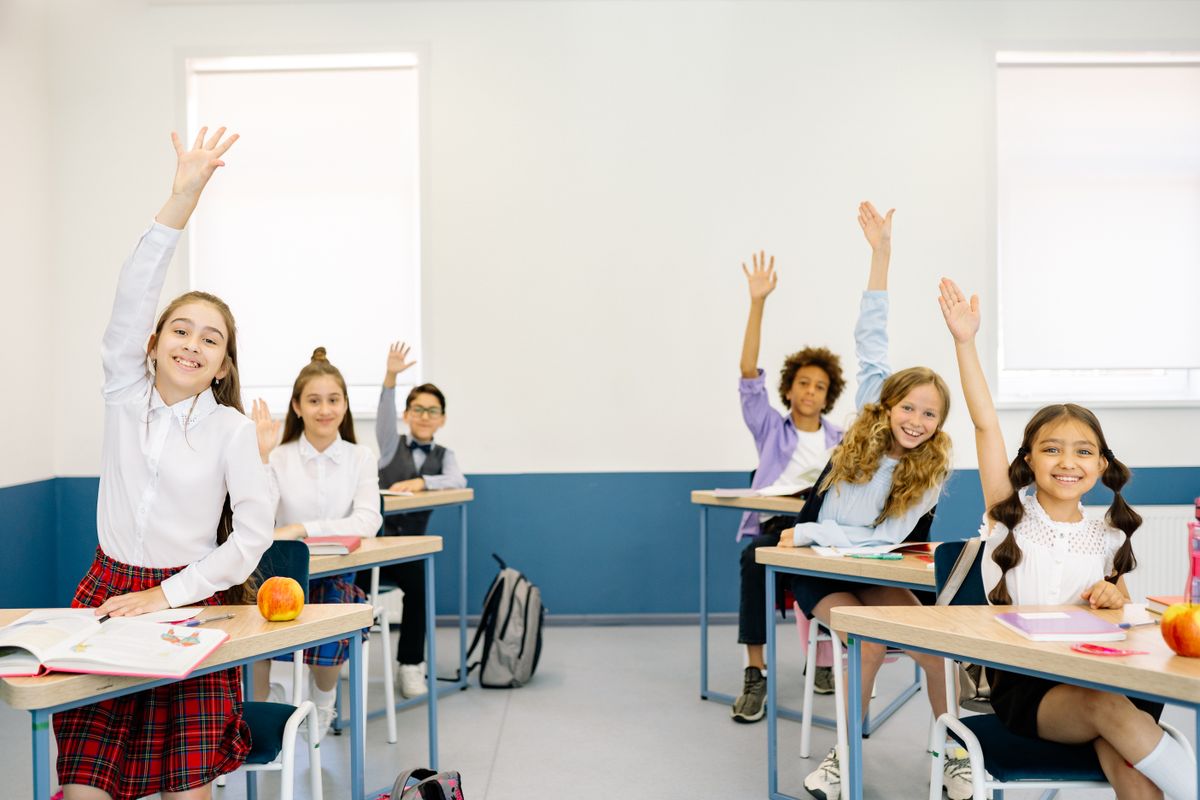 Happy students raising their hands in a classroom